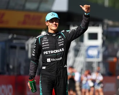 George Russell in black Petronas race suit waves to the crowd while holding a bottle