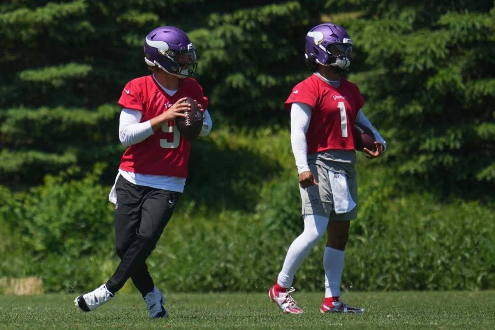 Minnesota Vikings quarterbacks J.J. McCarthy, holding a football in front of him in both hands, and Kyler Murray train during practice.