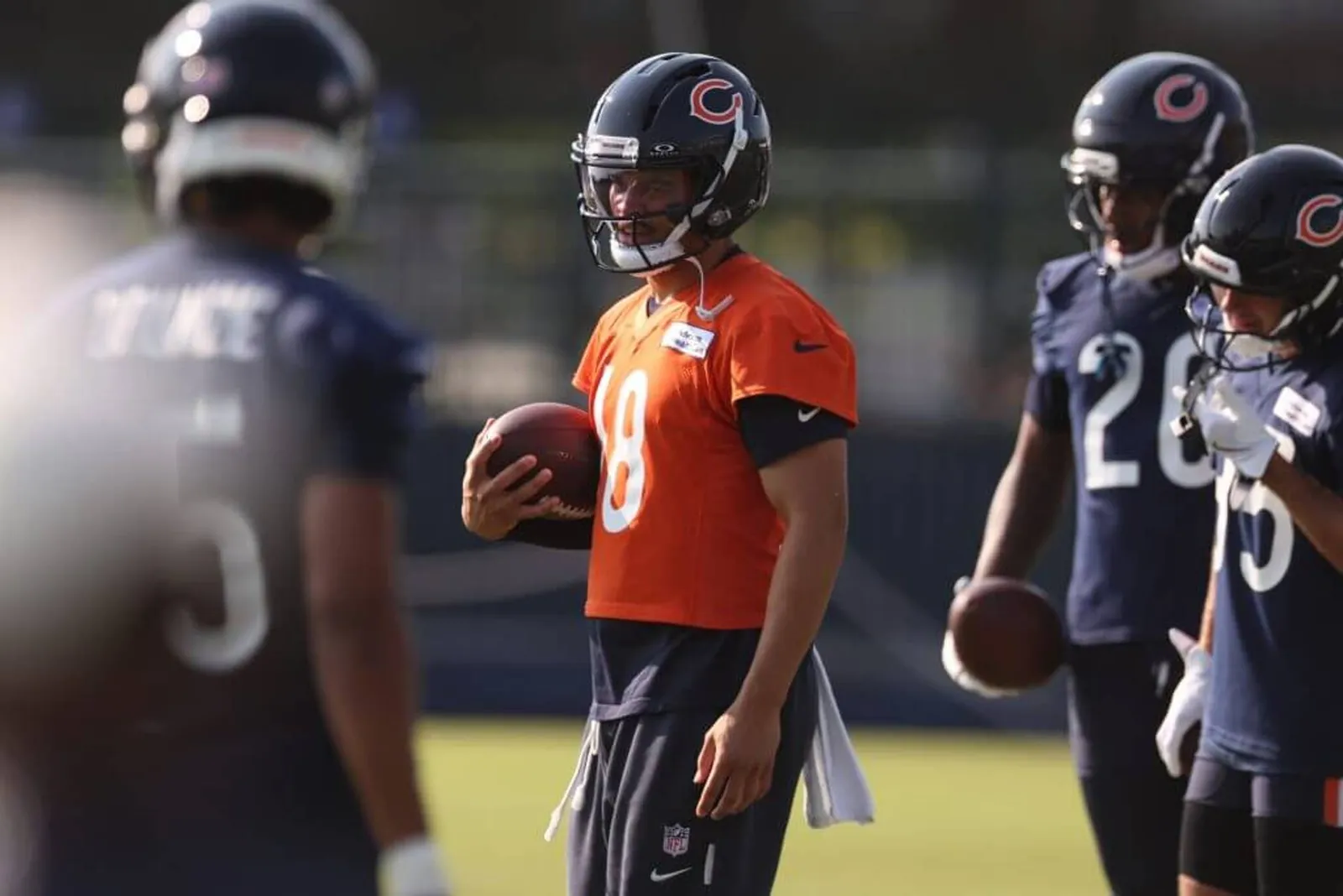 Bears quarterback Caleb Williams holds the ball in the middle of several players during training camp.